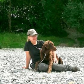 Trainerin Kirsten mit ihrem Hund Gustav auf dem Schoß
